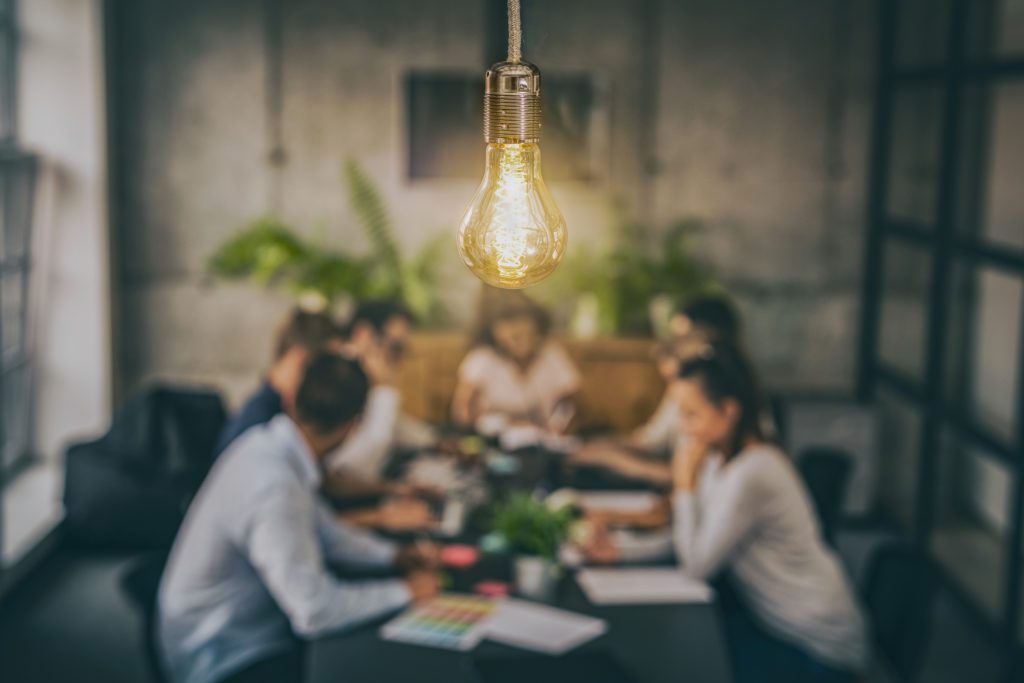 'lightbulb with a group of business people at a table in the background